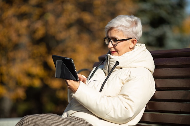 Mulher adulta sentada em um banco com um tablet