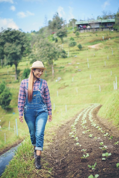 Mulher adulta sorridente caminhando por plantas em uma fazenda