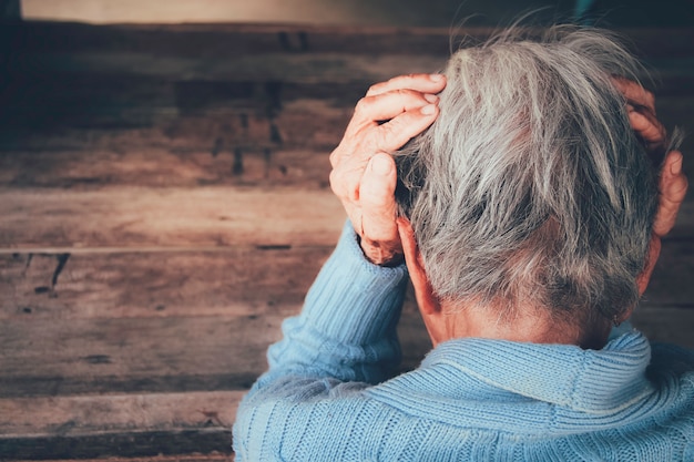 Foto mulher adulta tem dor de cabeça. ela sentada de cabeça nas mãos no quarto preto escuro. conceito dramática solidão, tristeza, depressão, emoções tristes, chorar, decepcionado, saúde, dor.