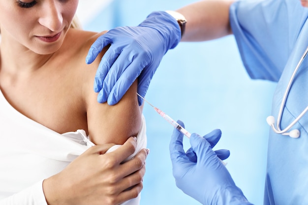 Mulher adulta tomando injeção durante visita ao consultório médico