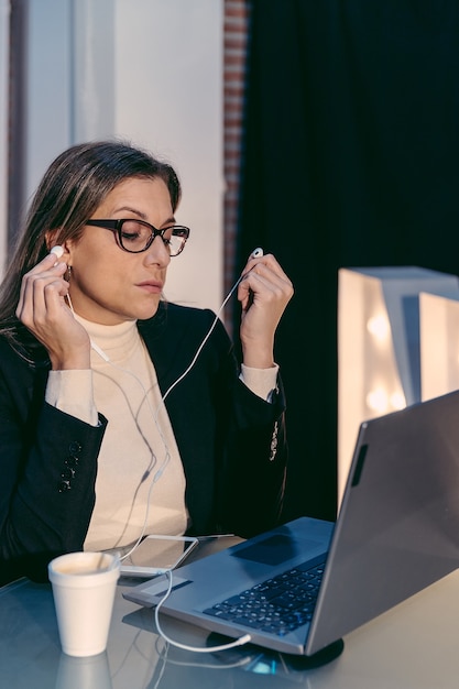 Mulher adulta usando laptop para videochamada enquanto está sentada em um moderno café-bar