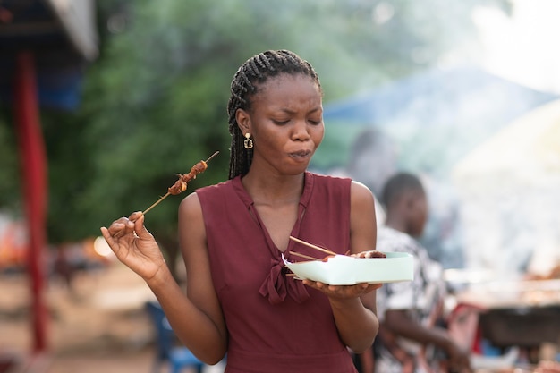 Foto mulher africana comendo comida de rua