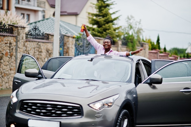 Mulher africana de negócios ricos no carro suv prata no teto solar se divertindo com cerveja na mão