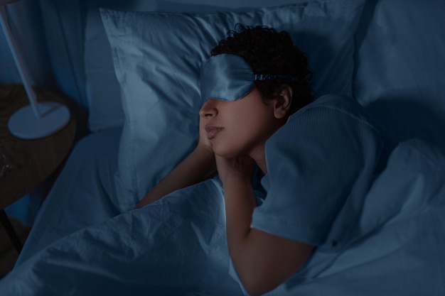 mulher africana dormindo na cama em casa à noite