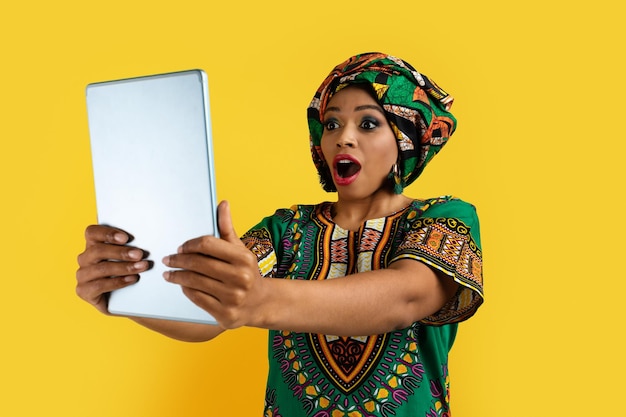 Foto mulher africana espantada olhando para o fundo amarelo da tela do teclado digital