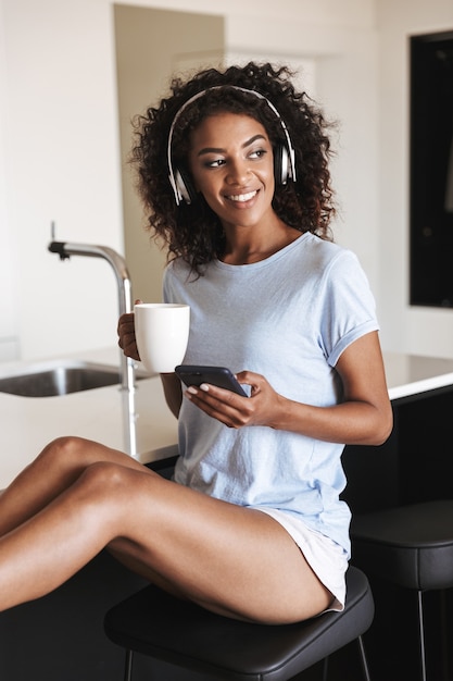 Mulher africana feliz com fones de ouvido e telefone celular