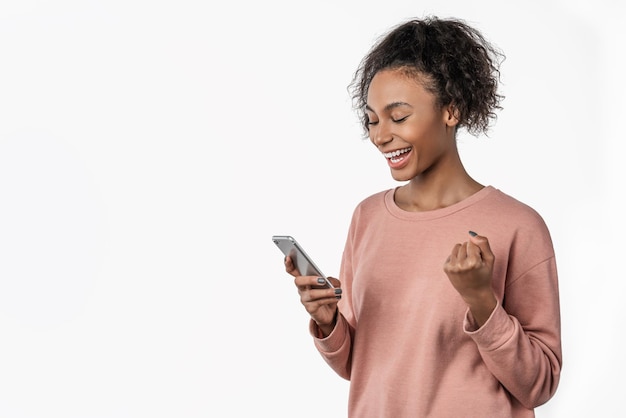 Mulher africana feliz comemorando com telefone celular isolado sobre fundo branco