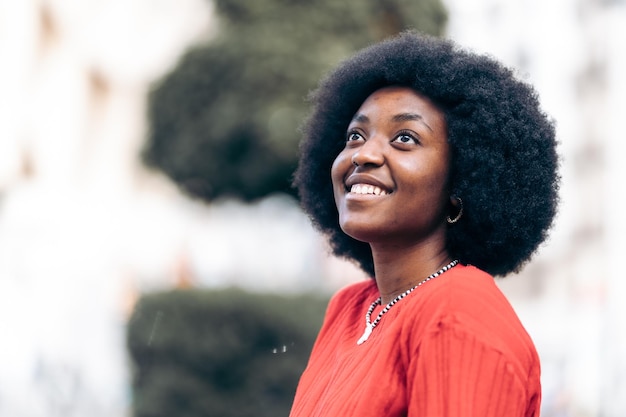 Mulher africana feliz e sonhadora olhando para o céu