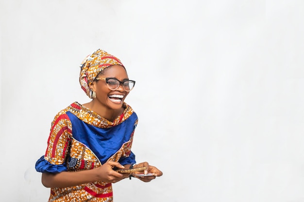 Mulher africana isolada sobre fundo branco rindo segurando telefone e cartão de crédito