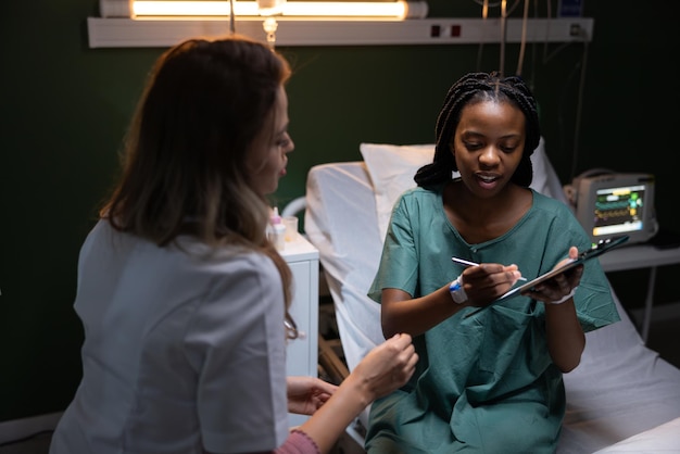 Mulher africana jovem na sala do hospital a assinar um acordo médico com o médico