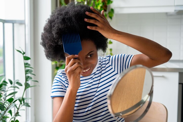 Foto mulher africana legal com pente saindo do cabelo encaracolado sorrindo olha no espelho e toca a peruca