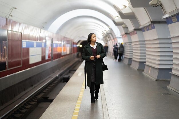 Mulher africana na plataforma vazia do metrô espera a chegada do trem tarde da noite, volta para casa do trabalho