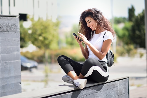 Mulher africana, ouvindo música com fones de ouvido e telefone inteligente