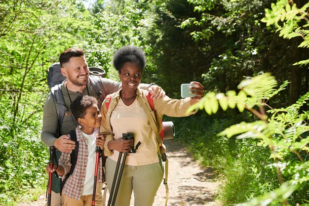 Mulher africana segurando um telefone celular e fazendo selfie um retrato de sua família durante a viagem na floresta