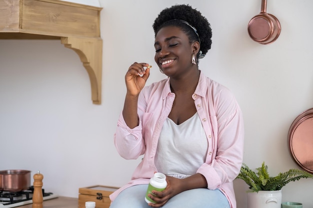 Foto mulher africana sentada na mesa com comprimidos nas mãos