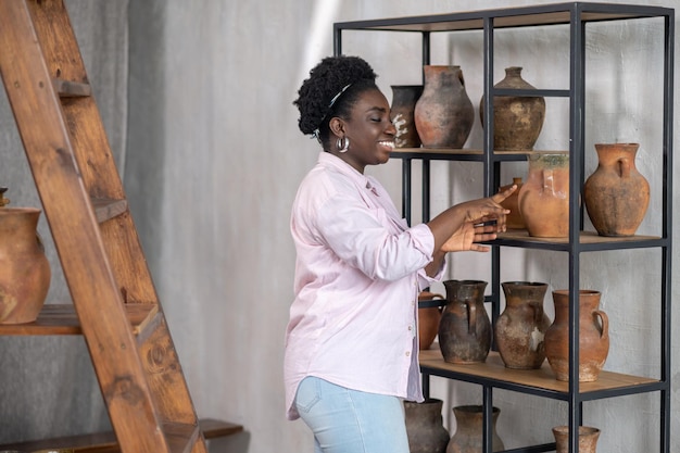Mulher africana sorridente em roupas cor de rosa no estúdio de cerâmica
