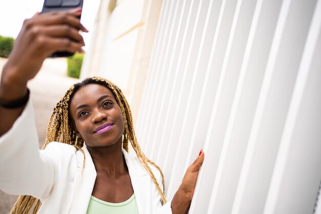 Mulher africana sorridente tirando uma selfie com o celular ao ar livre