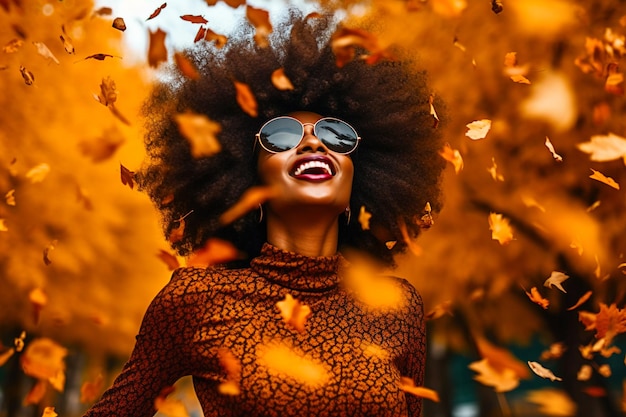 Mulher afro alegre com óculos de sol pretos rindo em meio a folhas caindo