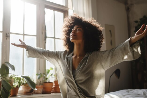 Foto mulher afro-americana acorda de manhã com os braços estendidos no quarto contra