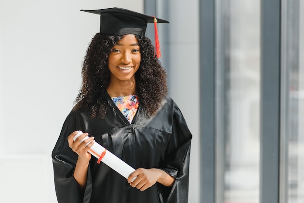 Foto mulher afro-americana alegre graduada em frente ao prédio da universidade