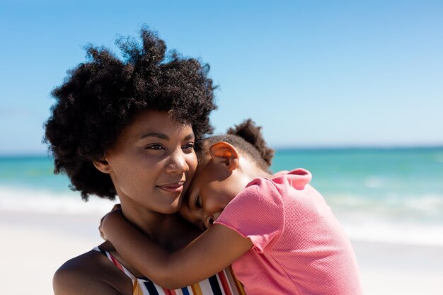 Mulher afro-americana com a filha na praia aproveitando o fim de semana de verão juntos