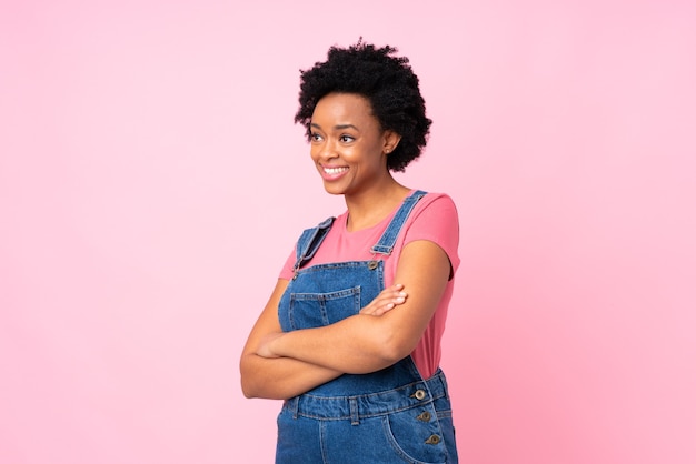 Mulher afro-americana com macacão rosa olhando para o lado