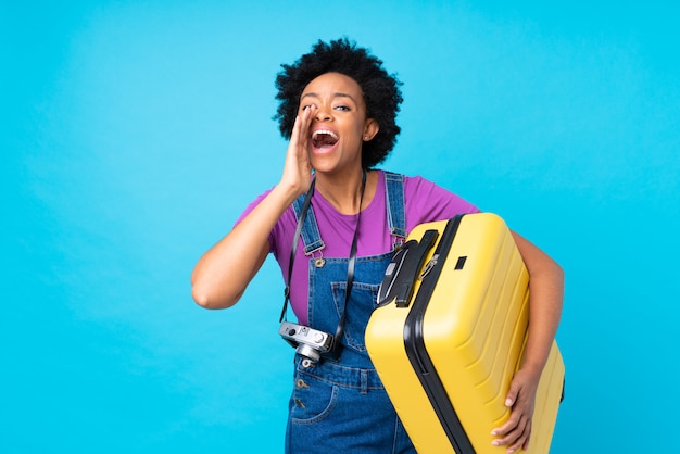 Foto mulher afro-americana com mala amarela sobre parede azul isolada