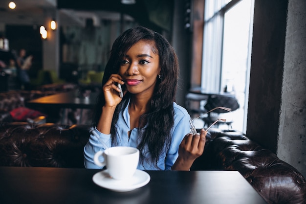 Mulher afro-americana com telefone em um café