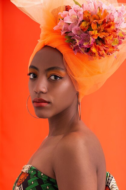 Mulher afro-americana com um arranjo de flores sobre fundo naranja