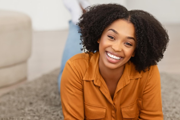 Mulher afro-americana com um sorriso cativante e cabelos ondulados.