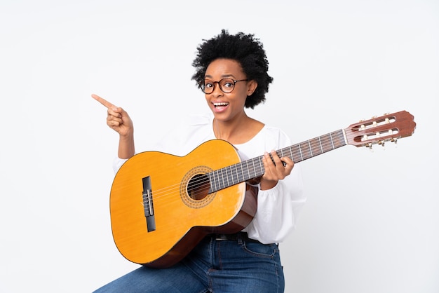 Mulher afro-americana com uma guitarra sobre parede branca isolada