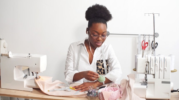 Foto mulher afro-americana costura roupas em seu estúdio favorito, oficina