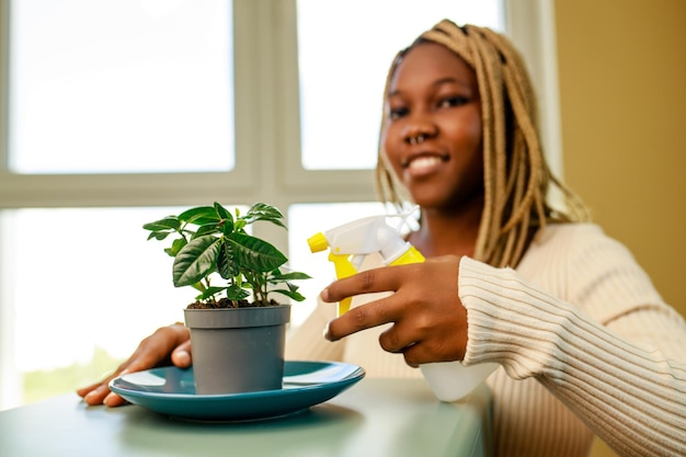 Mulher afro-americana cuidando e cultivando plantas em casa