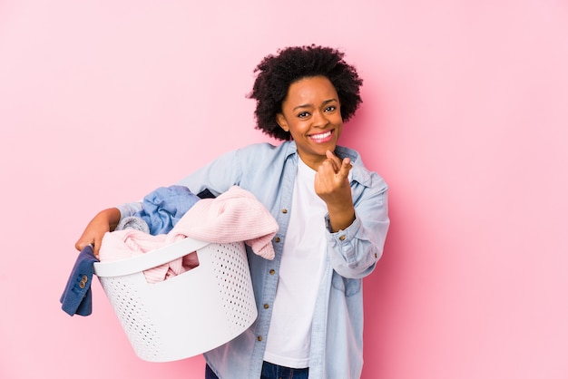 Mulher afro-americana da meia-idade lavando roupa isolada apontando com o dedo para você como se estivesse convidando se aproximar.