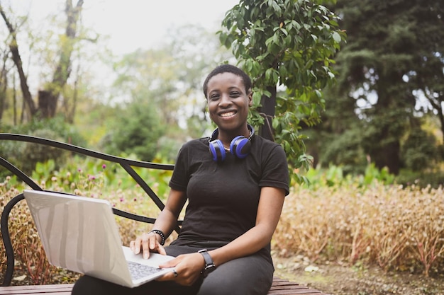 Mulher afro-americana de cabelos curtos, cabelo afro sorridente feliz com fones de ouvido azuis, estudando online