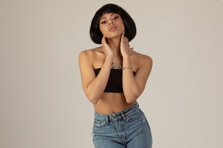 Mulher afro-americana de jeans posando em um fundo cinza