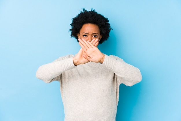 Mulher afro-americana de meia idade contra um fundo azul isolada fazendo um gesto de negação