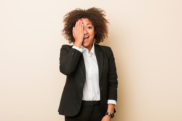 Mulher afro-americana de negócios jovem se divertindo cobrindo metade do rosto com a palma.