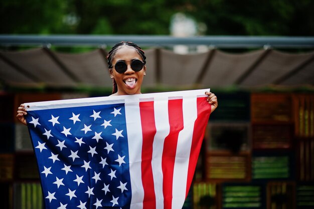 Mulher afro-americana elegante em óculos de sol posou ao ar livre com bandeira dos eua