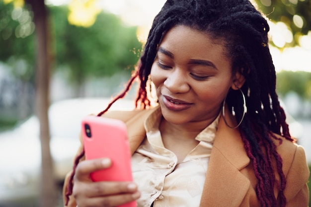 Mulher afro-americana em uma rua usando smartphone