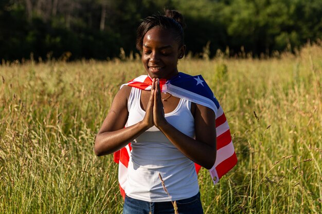 Mulher afro-americana envolta em bandeira americana