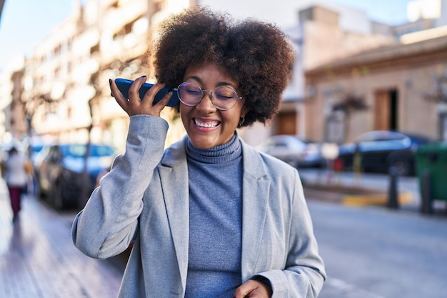 Mulher afro-americana executiva ouvindo mensagem de voz por smartphone na rua