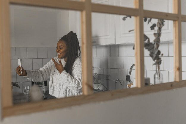 Foto mulher afro-americana fazendo videochamada em redes sociais de cozinha e conexão