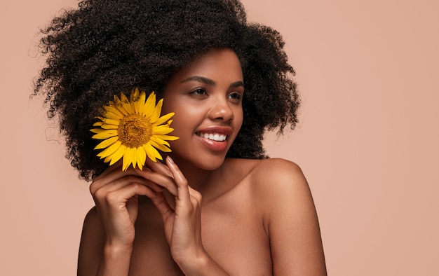 Mulher afro-americana feliz colocando uma flor no cabelo