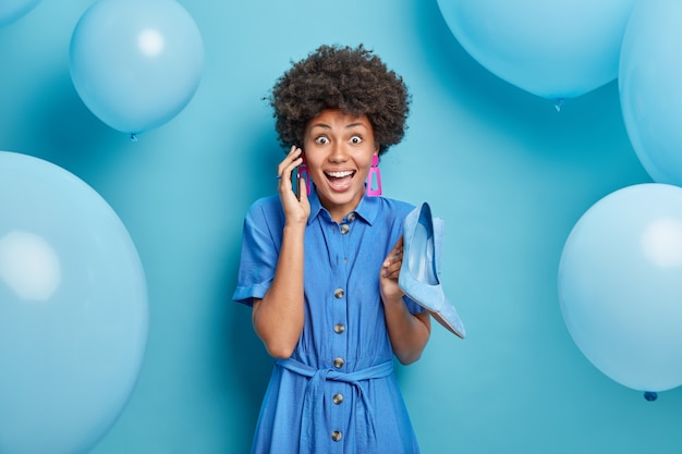 Mulher afro-americana feliz e animada com vestido azul e sapatos de salto alto vestidos para ocasiões especiais