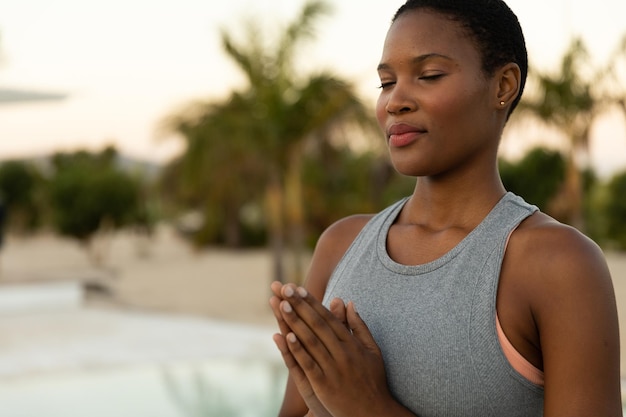 Mulher afro-americana feliz praticando meditação yoga na praia ensolarada, espaço de cópia. Estilo de vida saudável, relaxamento, bem-estar, verão e férias, inalterados.