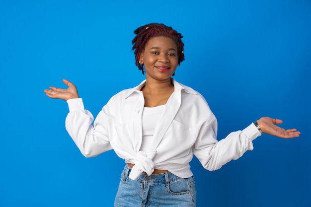 Mulher afro-americana hesitante dando de ombros contra um fundo azul