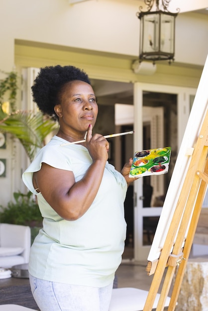 Mulher afro-americana idosa pensativa com uma paleta de pinturas em tela em casa, espaço de cópia. Estilo de vida dos idosos, aposentadoria, criatividade, hobbies, arte e vida doméstica, inalterados.