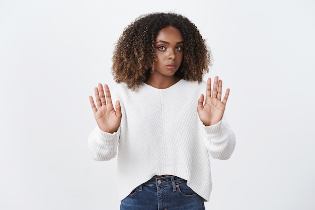 Mulher afro-americana intensa, desagradável e relutante, de aparência séria, ouvindo proposta perturbadora franzindo a testa e mostrando gesto de parar, recusando e mostrando rejeição