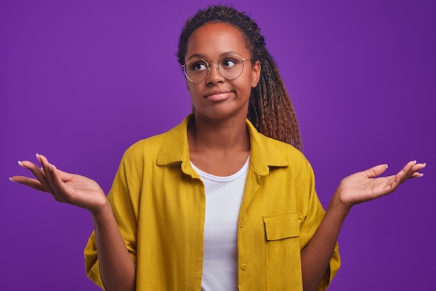 Mulher afro-americana jovem duvidosa franze os lábios e abre os braços para o lado